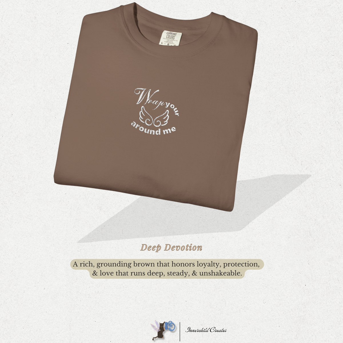 Folded brown, espresso t-shirt with text on a light gray background. Embroidered white wings. 