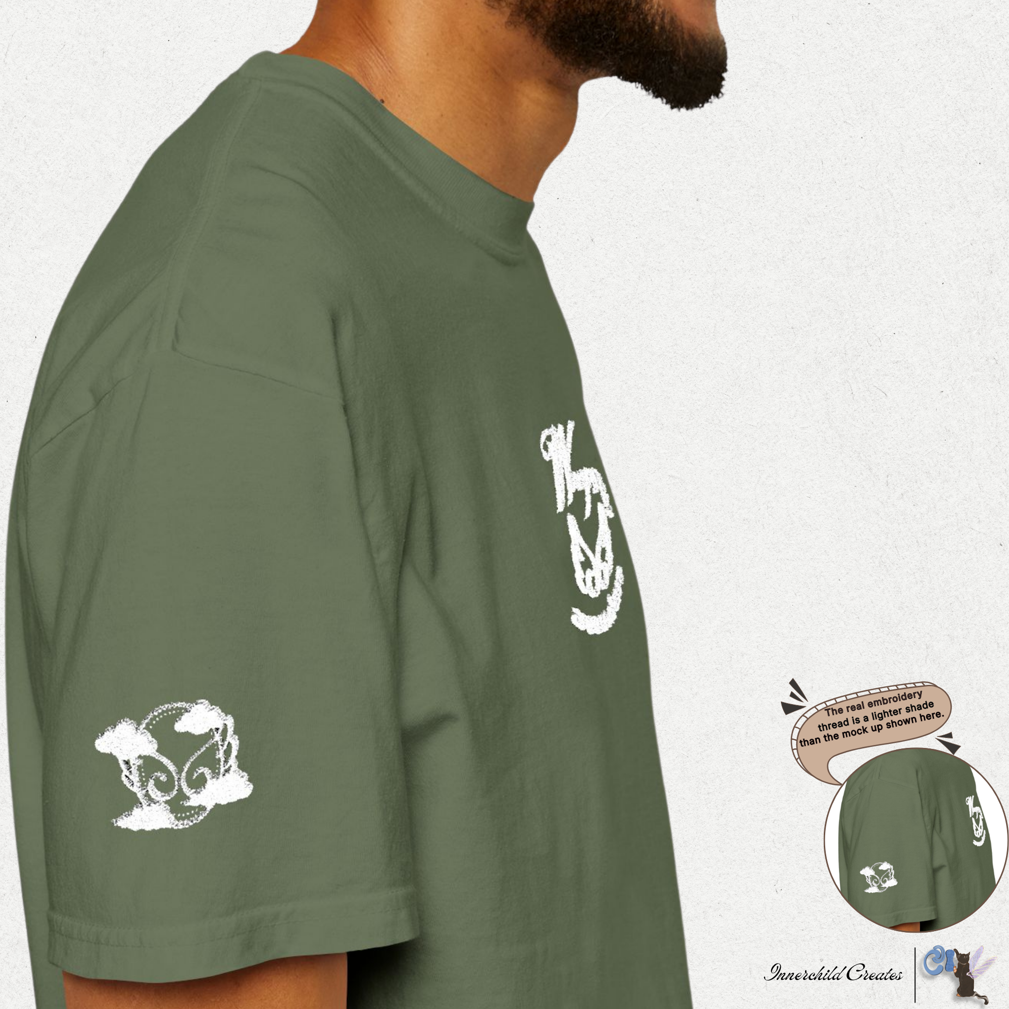 Green shirt with white graphics worn by a person, on a plain background. Sage right sleeve white wings and clouds embroidery. 